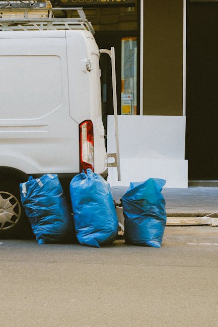 A large pile of black garbage bags filled with waste materials is situated outdoors against a tiled wall with a graffiti message reading 'XEND' spray-painted in red. The bags are tightly packed and st